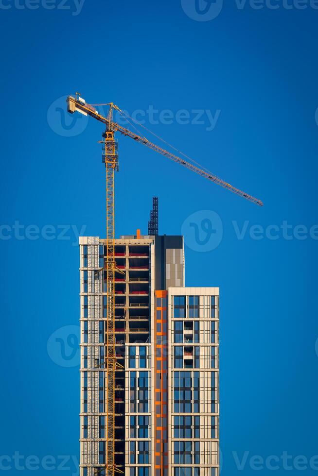 een kraan gebouw een wolkenkrabber tegen een blauw lucht. foto