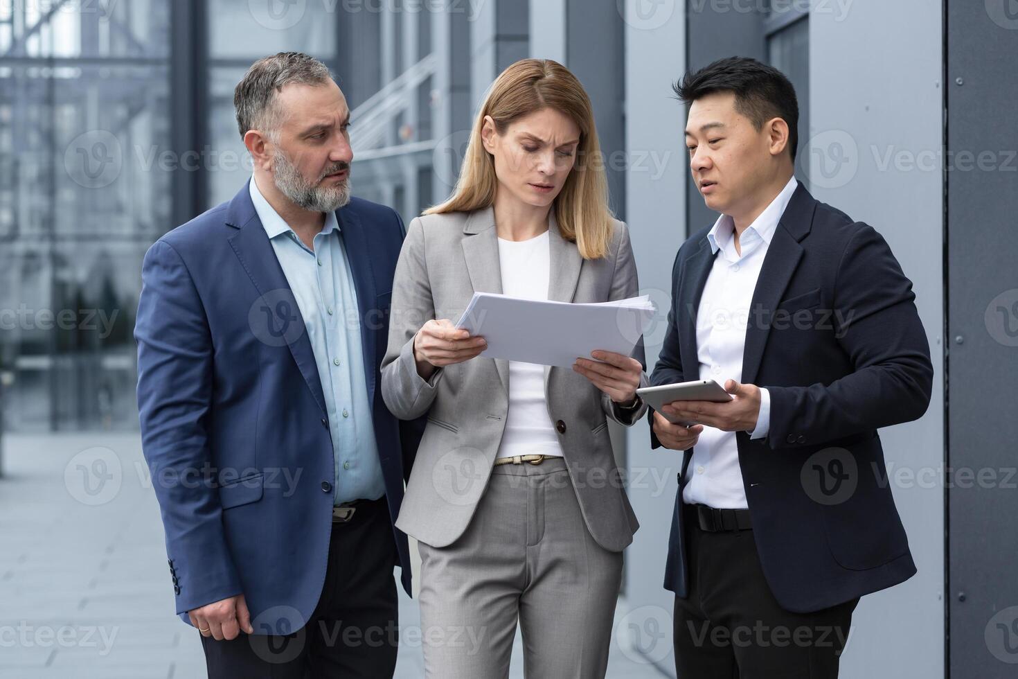 verschillend bedrijf team drie collega's medewerkers bespreken documenten contract buiten kantoor gebouw zakenman en zakenvrouw Holding rekeningen en financieel rapporten pratend foto