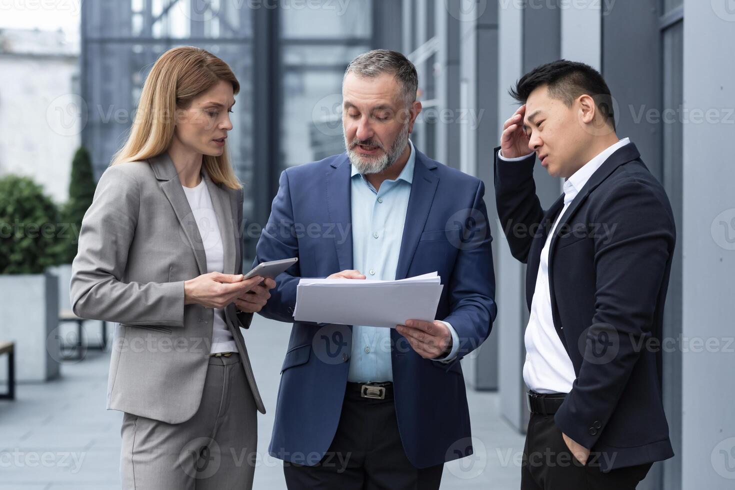 verschillend bedrijf groep van drie collega's arbeiders, van streek en teleurgesteld, resultaat van financieel verslag doen van en contract document, bedrijf arbeiders buiten kantoor gebouw in bedrijf pakken praten. foto