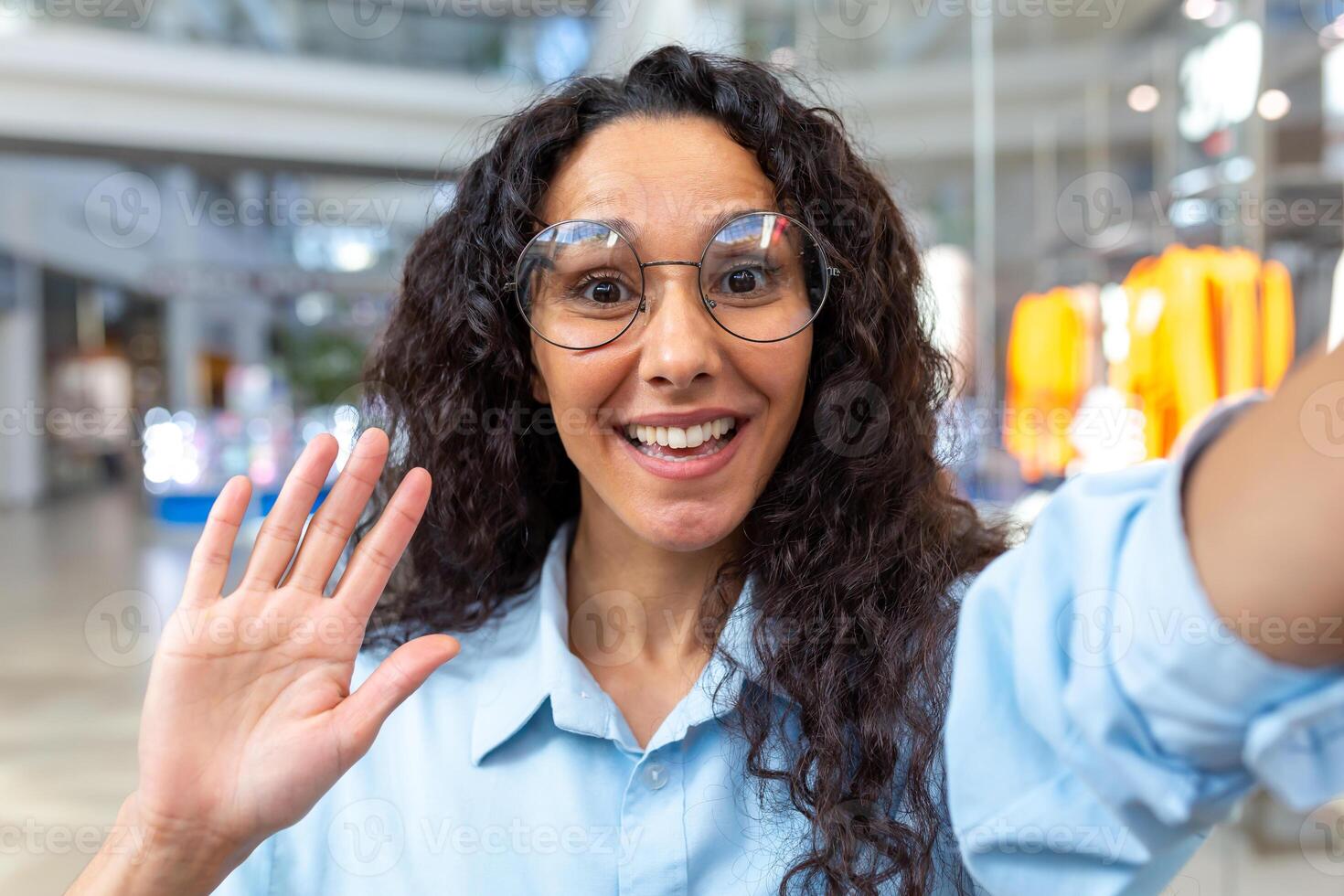 een jong mooi Latijns Amerikaans vrouw is staand in een boodschappen doen centrum, pratend Aan een telefoontje foto