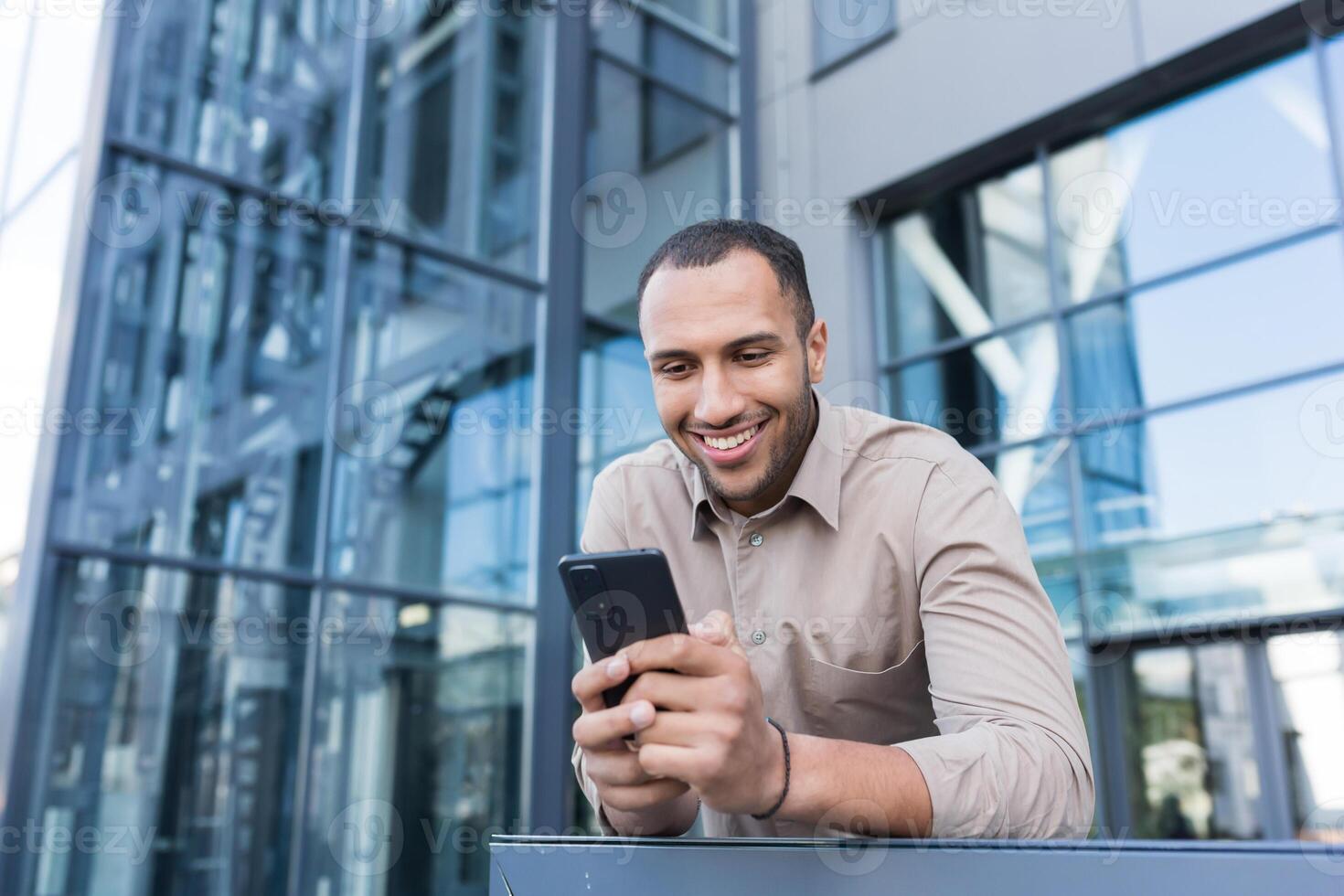 geslaagd zakenman buiten modern kantoor gebouw gebruik makend van smartphone, Mens lezing bericht en browsen web Pagina's, Afrikaanse Amerikaans Mens in overhemd Holding telefoon typen bericht. foto