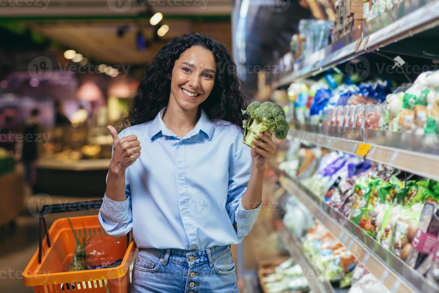 portret van een mooi vegetarisch vrouw in een supermarkt, een spaans vrouw glimlachen en op zoek Bij de camera en glimlachen kiest broccoli groenten in een kruidenier op te slaan foto