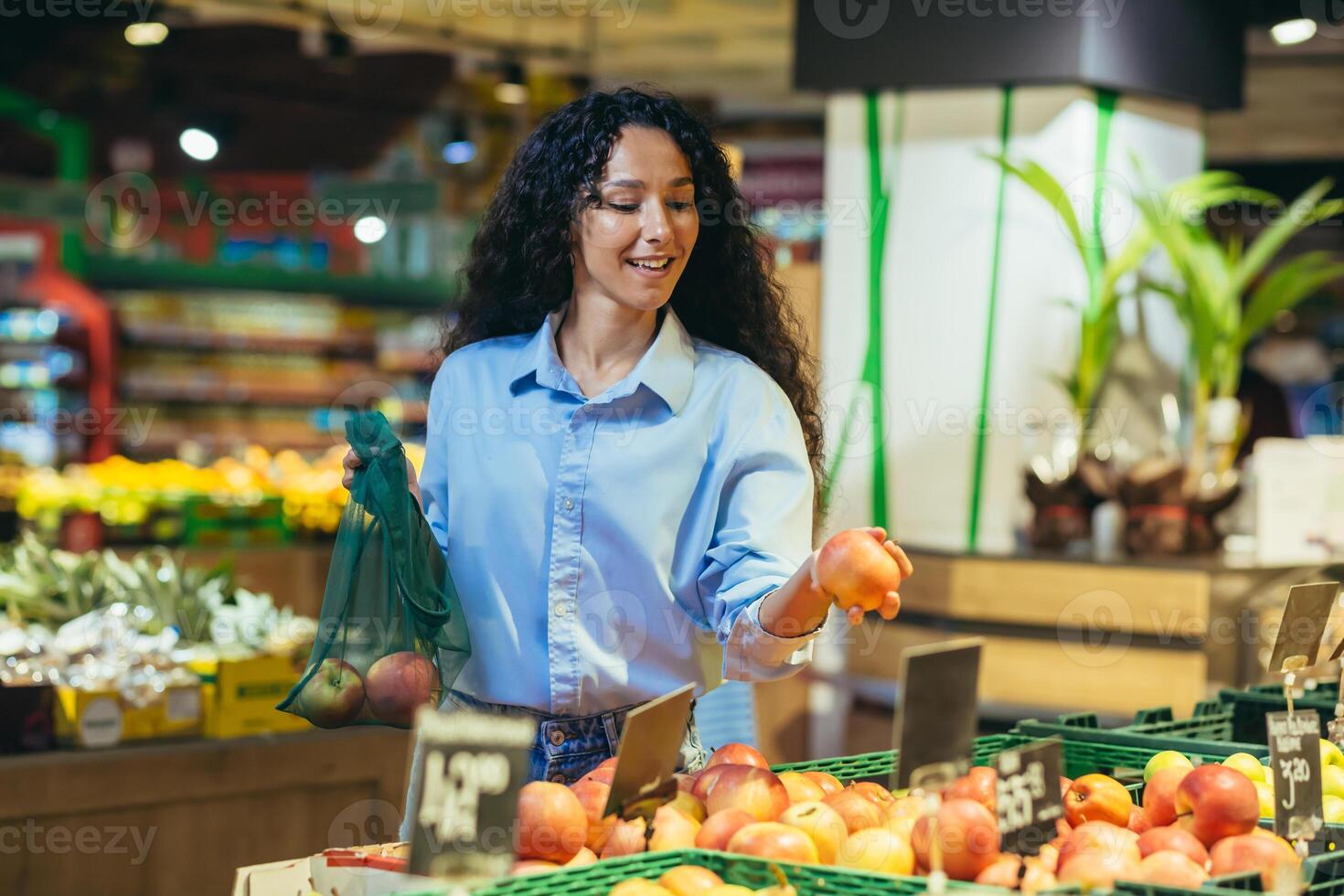 glimlachen Latijns Amerikaans bedrijf vrouw kiest en koopt vers appels, fruit in de supermarkt foto