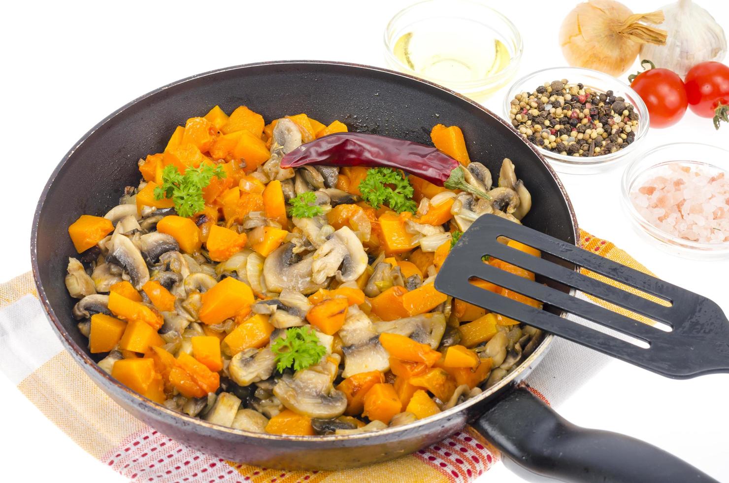 vegetarische groentestoofpot van pompoen en champignons in pan, witte achtergrond. foto