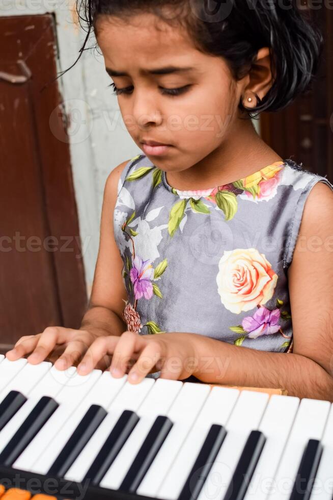 Aziatisch schattig meisje spelen de synthesizer of piano. schattig weinig kind aan het leren hoe naar Speel piano. kind handen Aan de toetsenbord binnen. foto