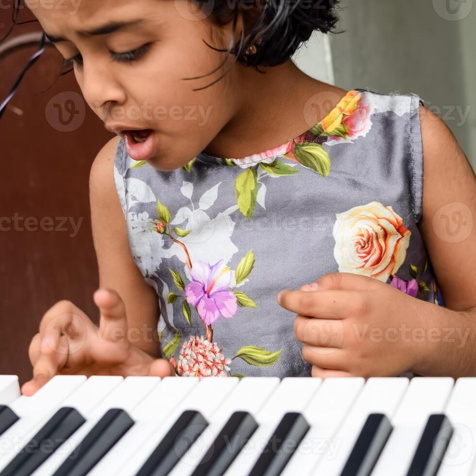 Aziatisch schattig meisje spelen de synthesizer of piano. schattig weinig kind aan het leren hoe naar Speel piano. kind handen Aan de toetsenbord binnen. foto