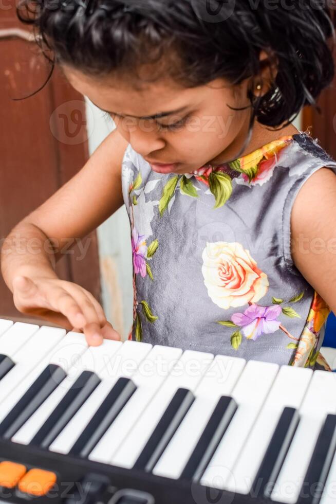 Aziatisch schattig meisje spelen de synthesizer of piano. schattig weinig kind aan het leren hoe naar Speel piano. kind handen Aan de toetsenbord binnen. foto