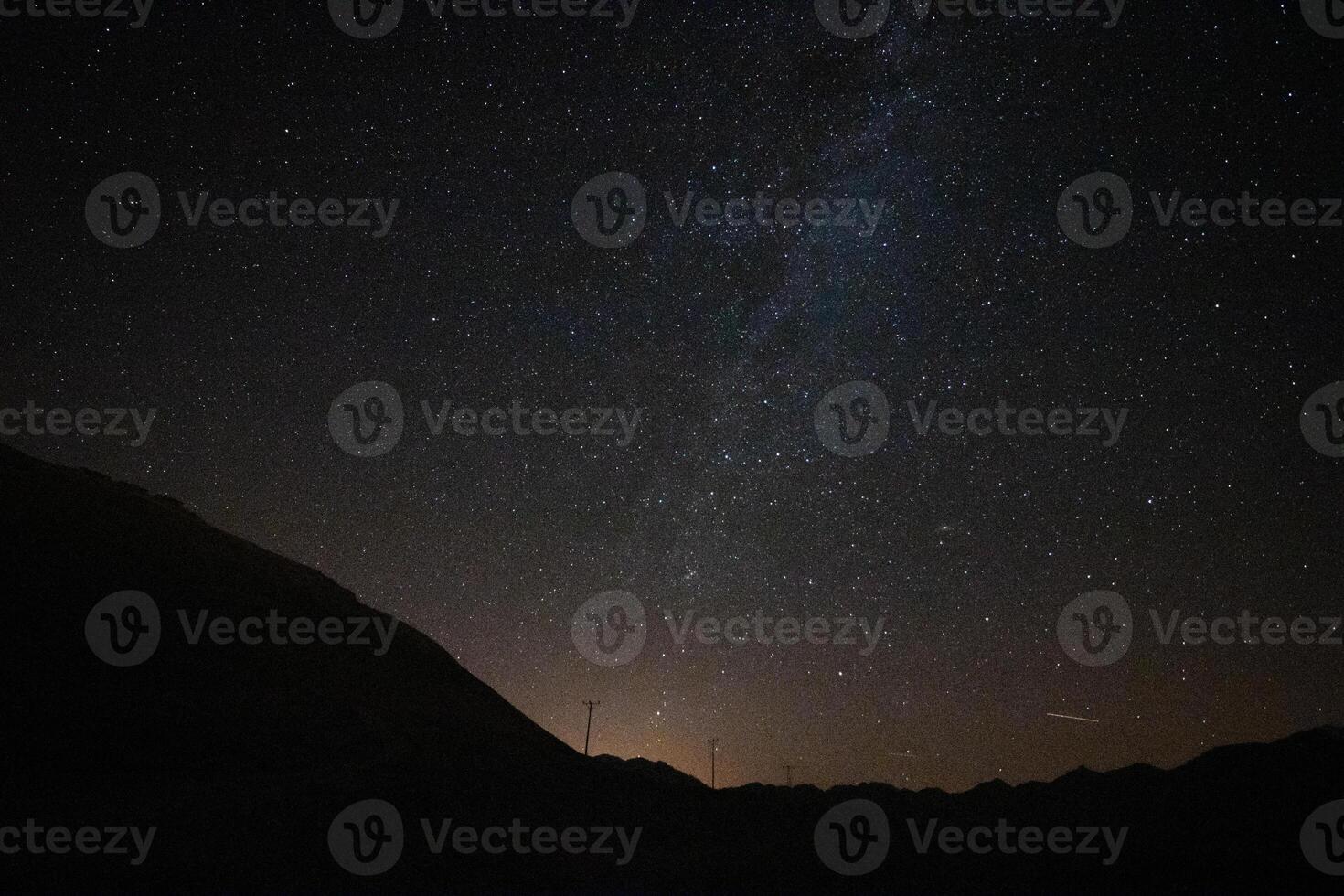 melkachtig manier over- de silhouet van de heuvels en stad lichten Bij nacht foto