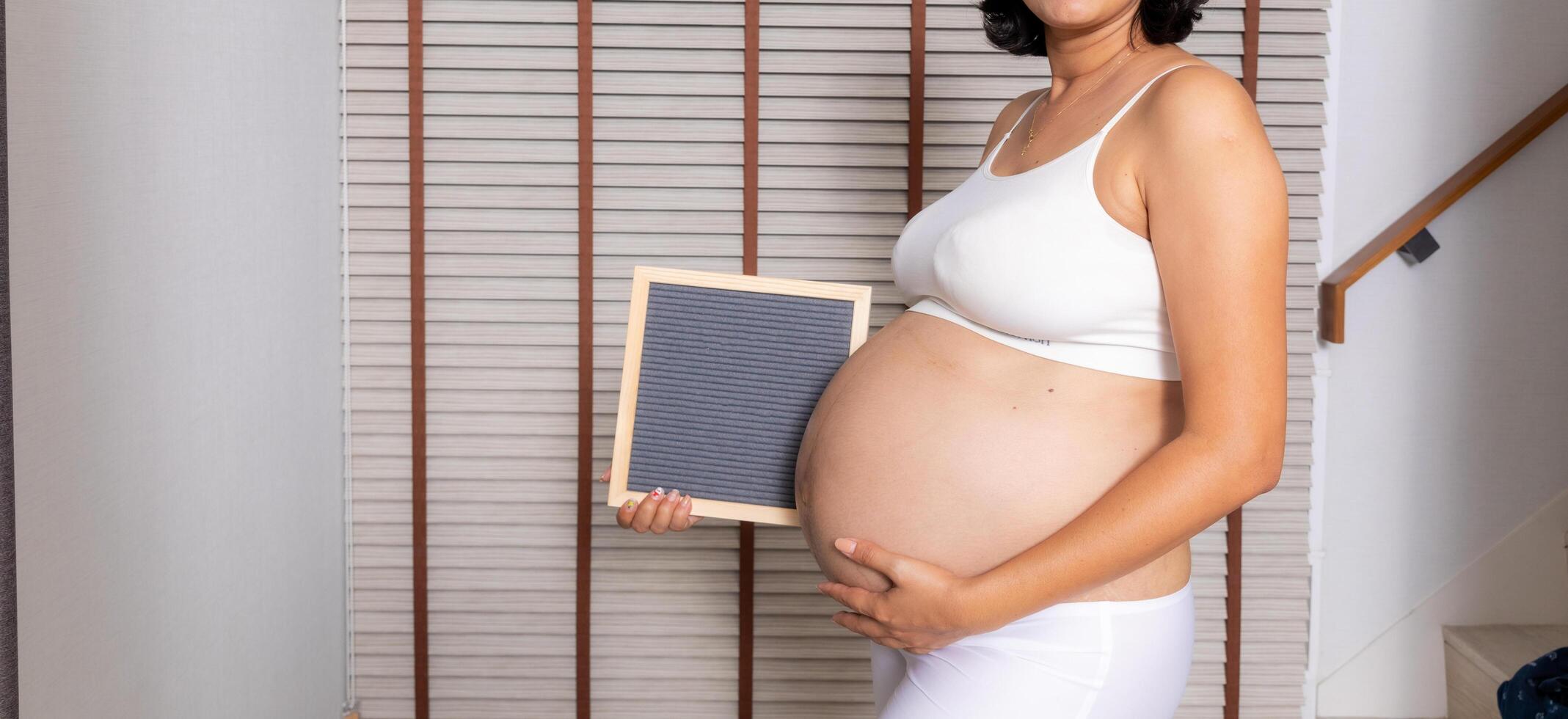 groot zwanger vrouw met brief bord foto