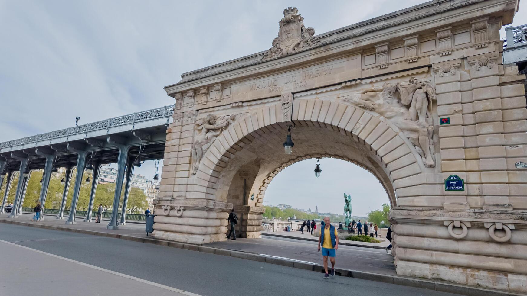 toerist verkennen de historisch pont de bir hakeim versierd met sculpturen over- de Seine rivier- in Parijs, Frankrijk, Aan een bewolkt voorjaar dag, april 14e, 2024 foto