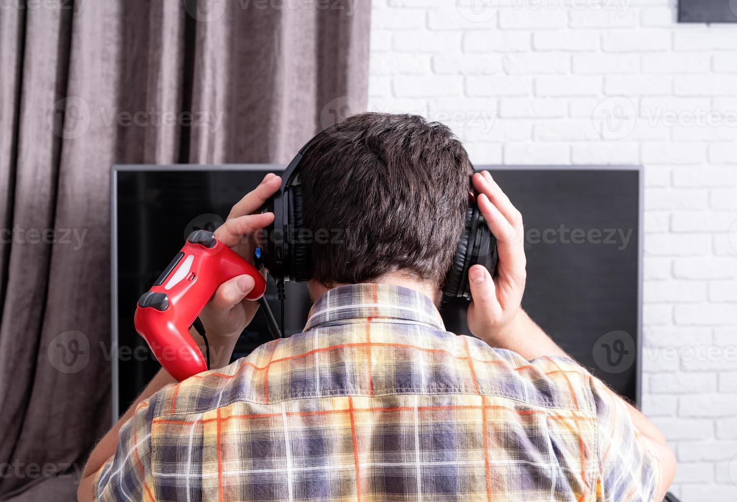 achteraanzicht van een jonge man die thuis videogames speelt foto