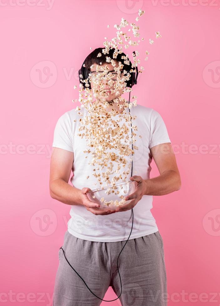 jonge grappige man popcorn in de lucht gooien geïsoleerd op roze foto