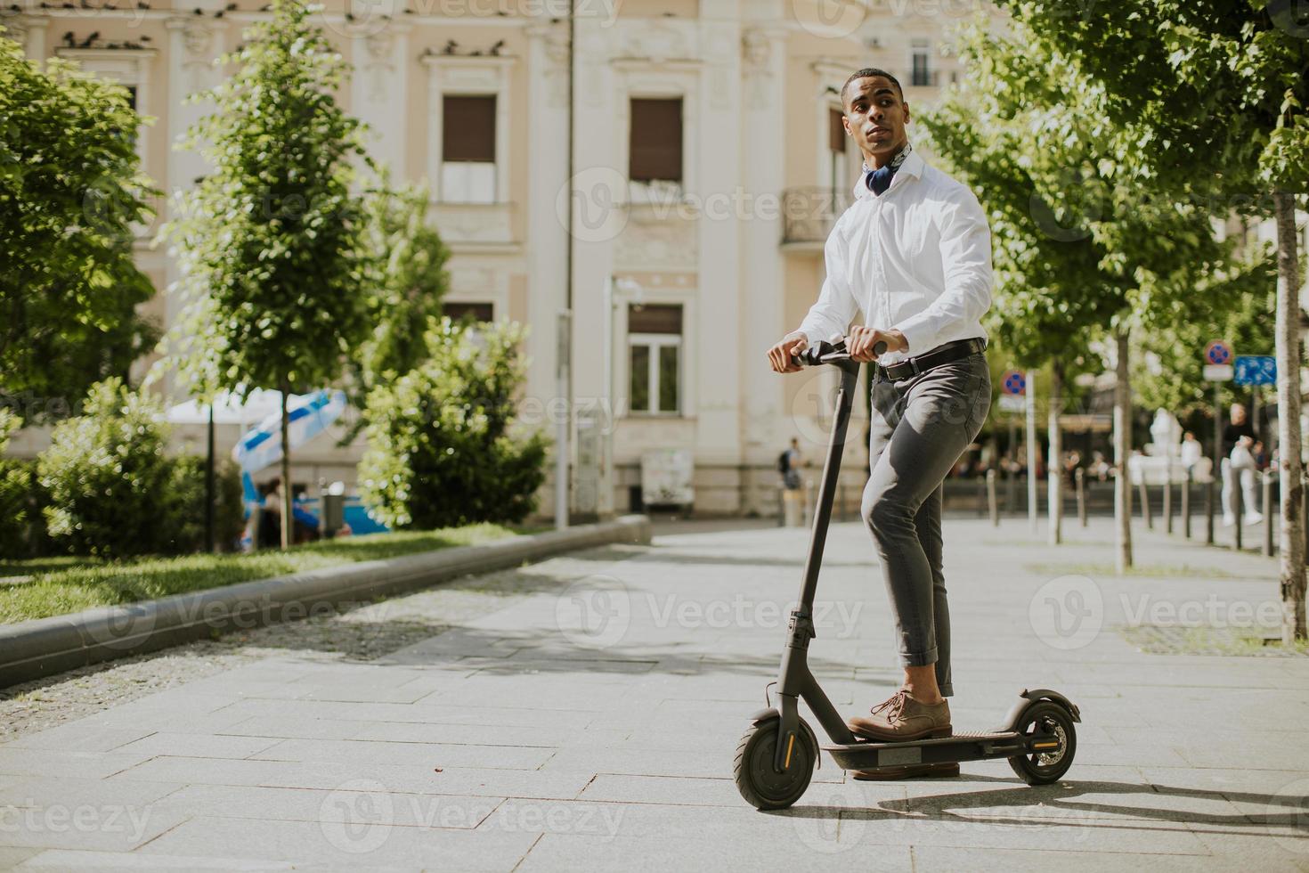 jonge Afro-Amerikaanse met behulp van elektrische scooter op een straat foto