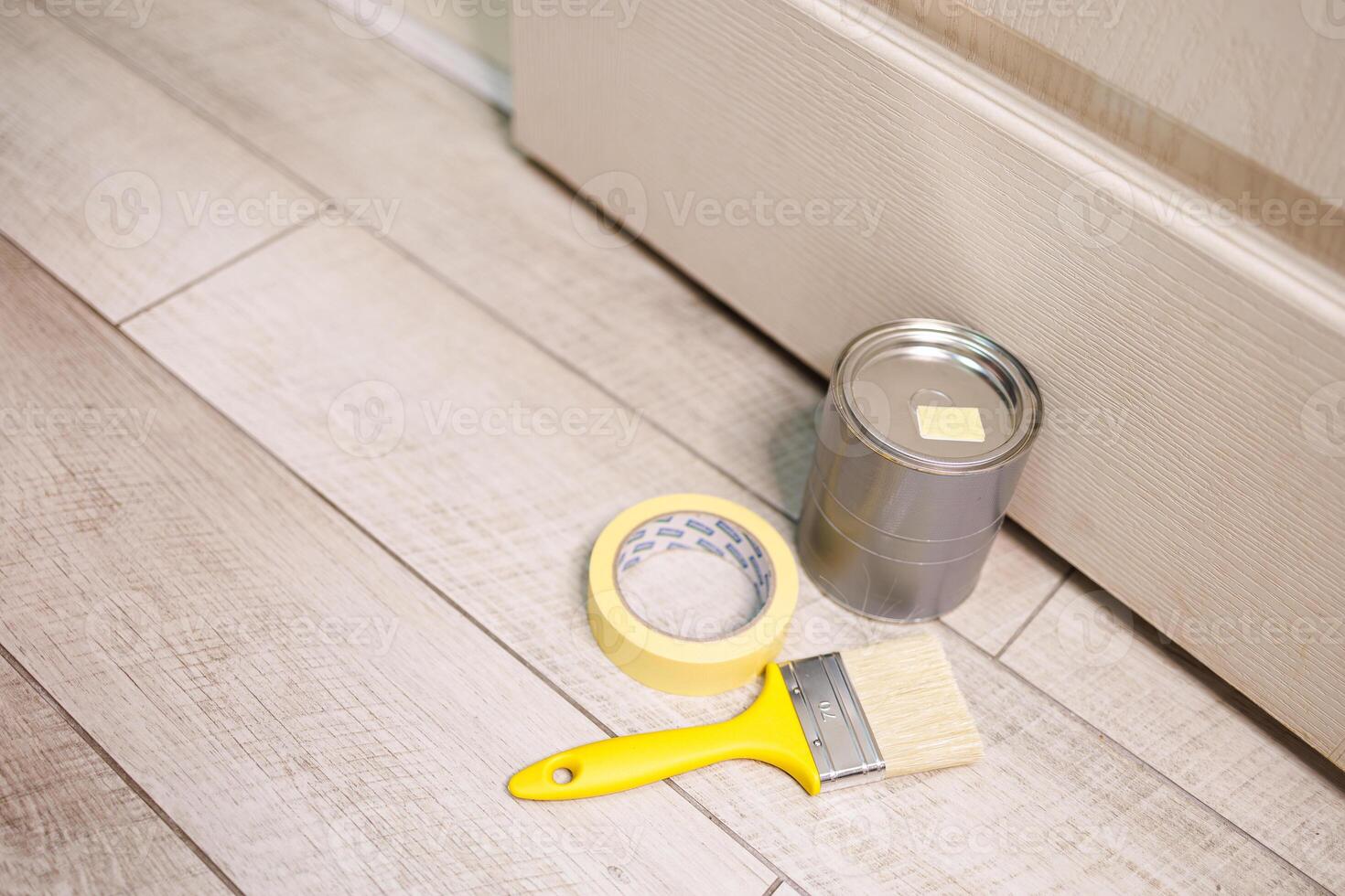 een kan van verf en een penseel zijn Aan de vloer. reparatie kleuring de deuren met verf. foto