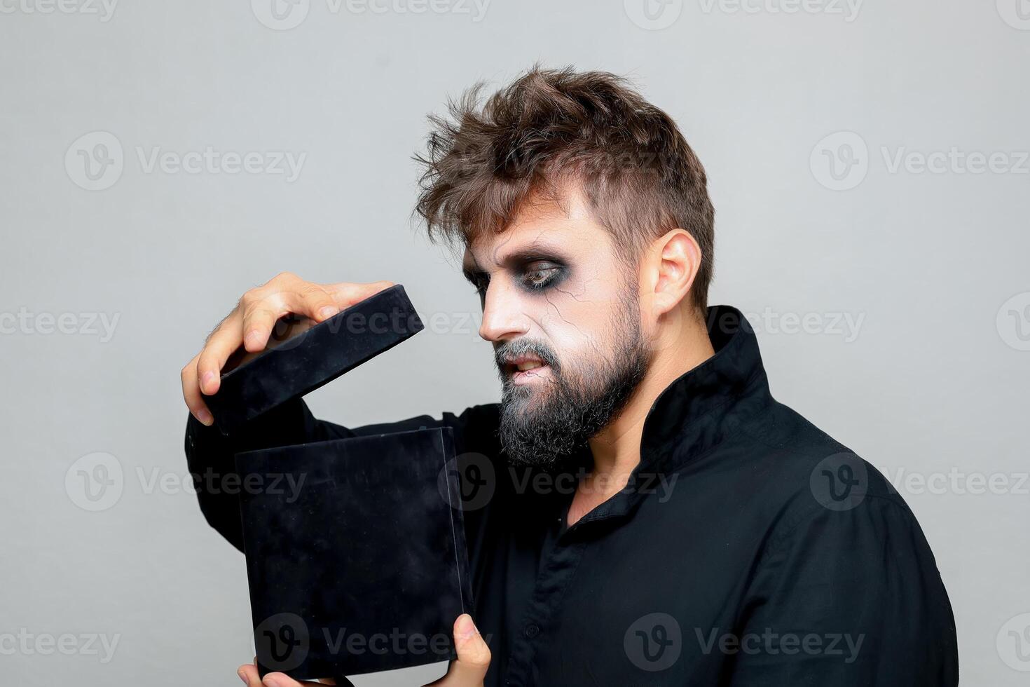 een gebaard Mens met ondode stijl bedenken opent een zwart doos voor halloween foto