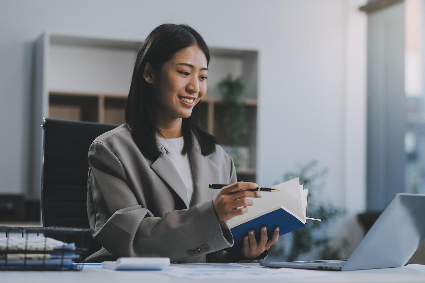 zelfverzekerd millennial Indisch vrouw bedrijf analist financieel adviseur voorbereidingen treffen statistisch verslag doen van aan het studeren documenten Aan werk bureau, browsen informatie online gebruik makend van pc, schrijven uit aantekeningen Aan papier vel foto