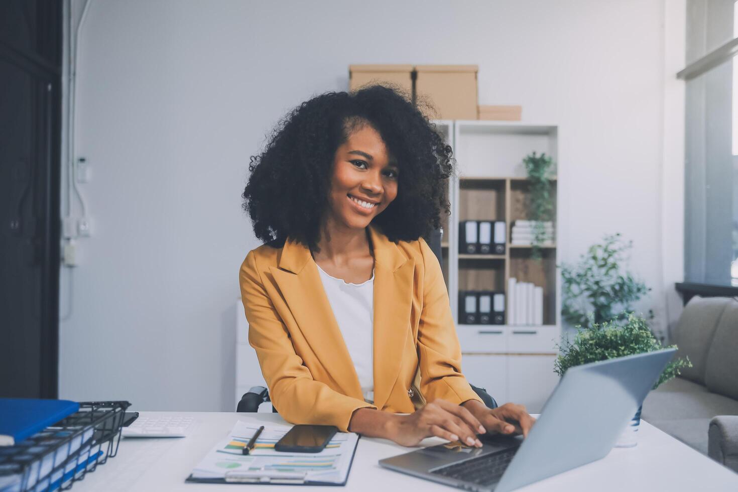 Aziatische zakenvrouw die een laptopcomputer gebruikt en op kantoor werkt met een rekenmachinedocument op het bureau, planning analyseert van het financiële rapport, businessplaninvestering, financiële analyseconcept. foto