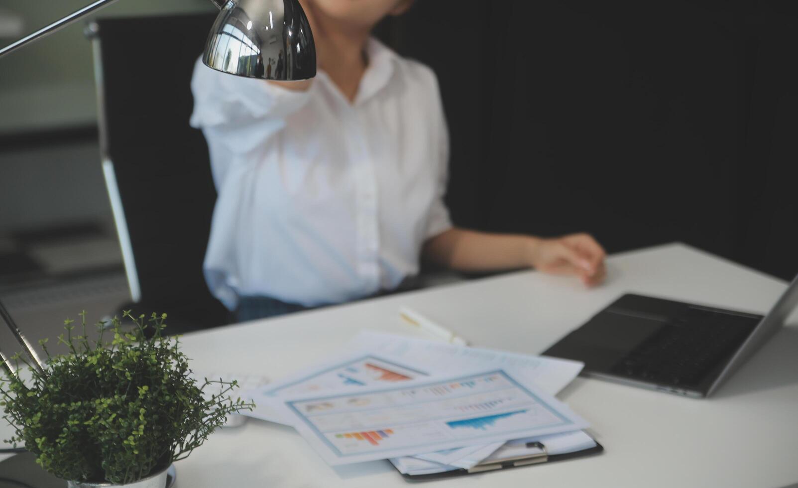 jonge aziatische vrouw die migrainehoofdspanning voelt. vermoeide, overwerkte zakenvrouw financier tijdens het werken op laptopcomputer op kantoor. foto