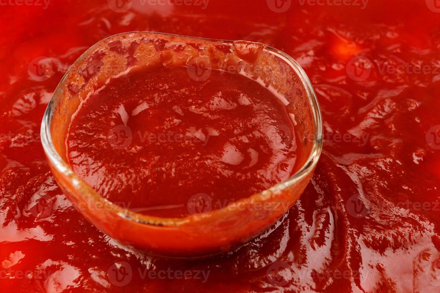 tomaat saus . glas kop met resterend ketchup en ketchup gemorst in de omgeving van het. foto
