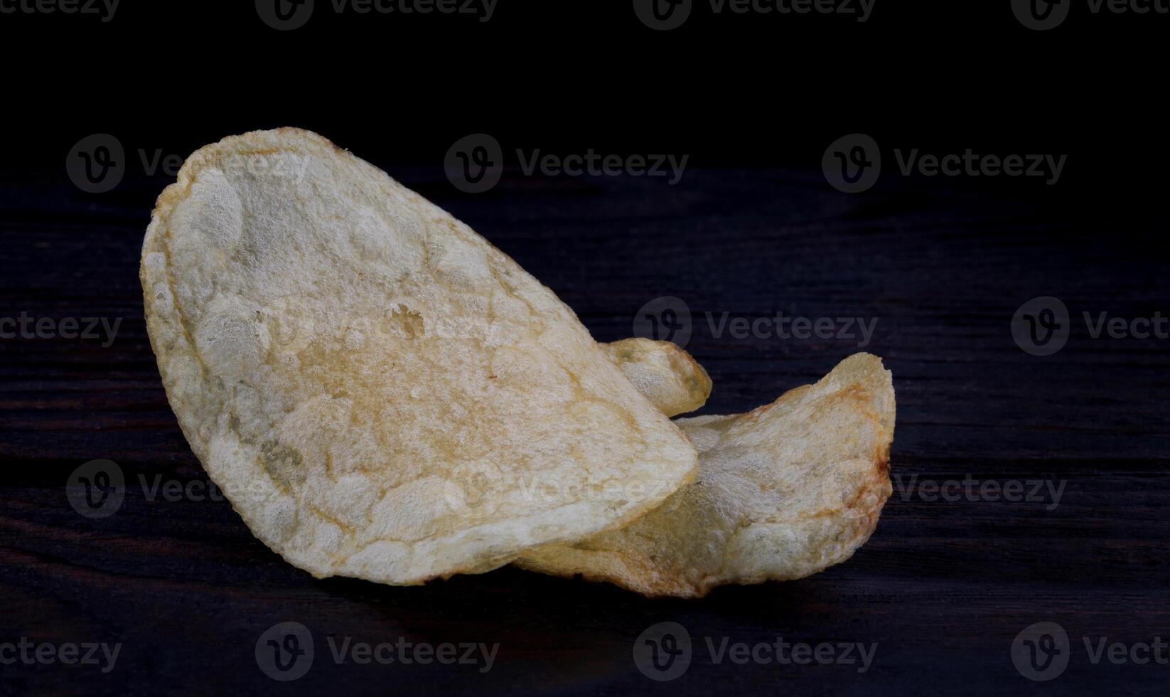 aardappel chips Aan een donker achtergrond. chips Aan een houten bord foto