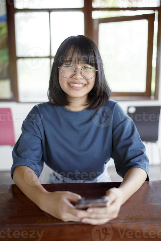 Aziatische tiener toothy glimlachend met geluk en mobiele telefoon in de hand houden foto