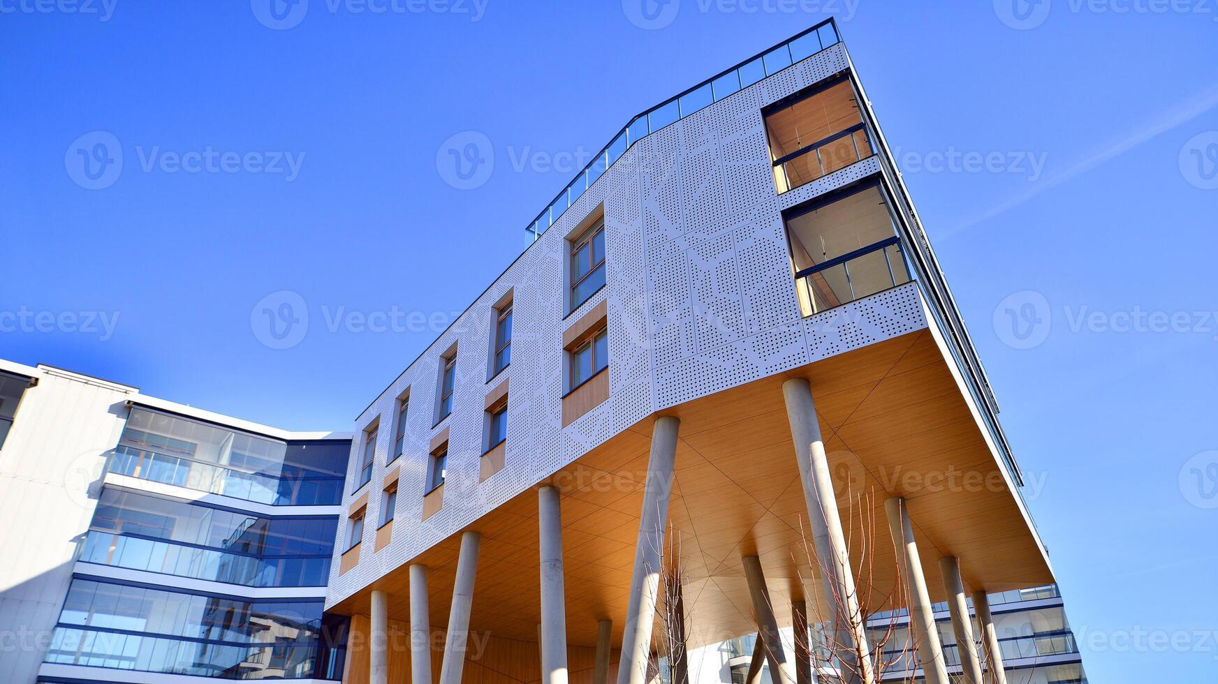 een appartement gebouw met een uniek bouwkundig oplossing. een modern woon- gebouw met een wit facade en staand Aan hoog beton pijlers. foto