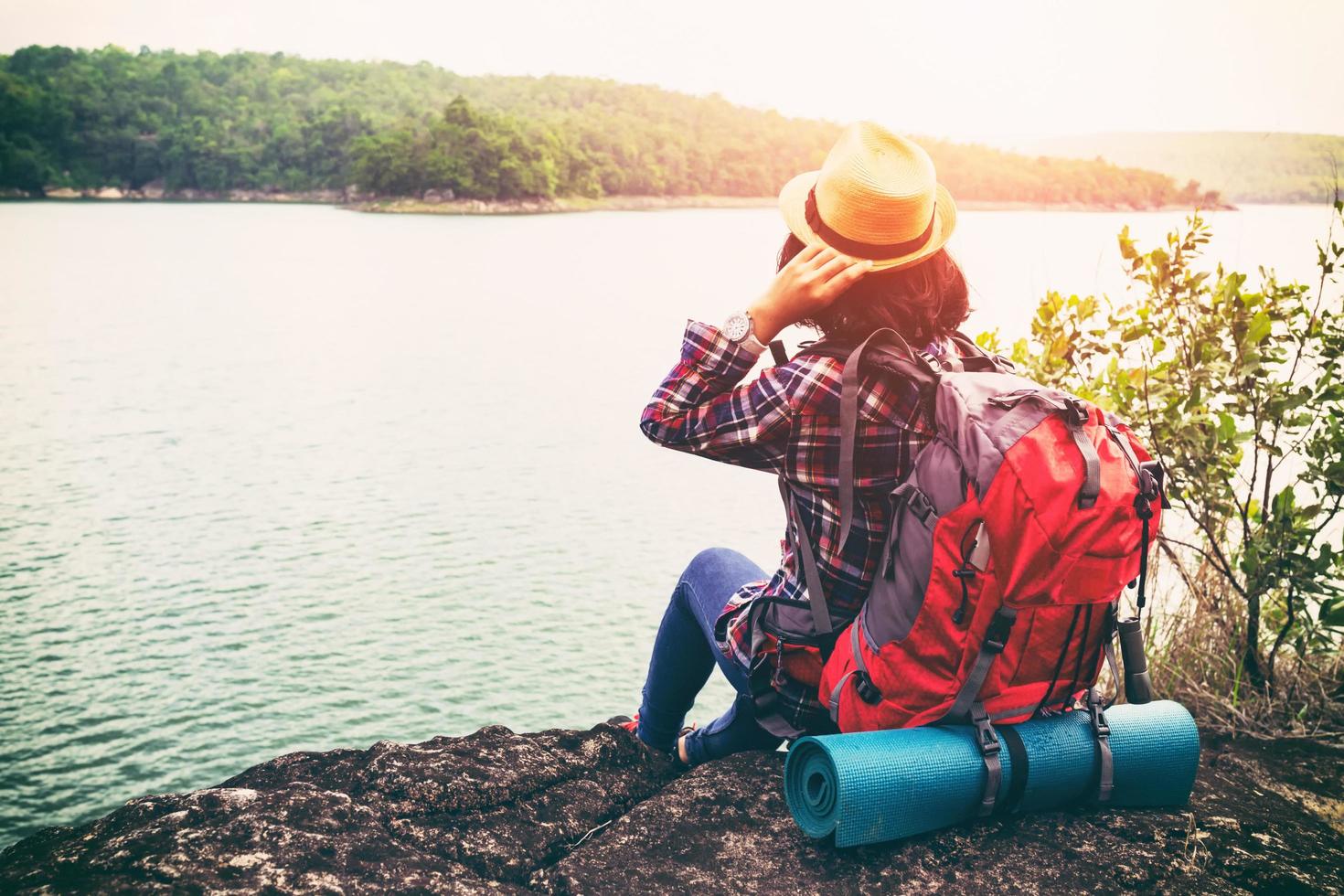 jonge hipster vrouw met backpacker zittend op steen genieten van uitzicht op het meer en de bergen van het prachtige landschap. dit reizigersgeluk met reis in avontuur van levensstijl vrijheid vrouwen sterker foto
