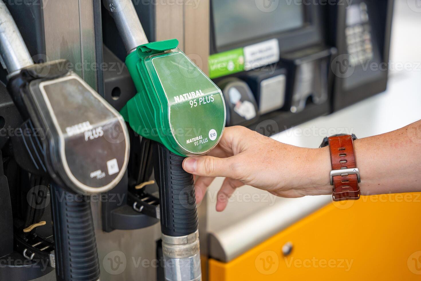 Mens Holding een benzine mondstuk in zijn hand- Aan Zelfbediening vulling station in Europa foto