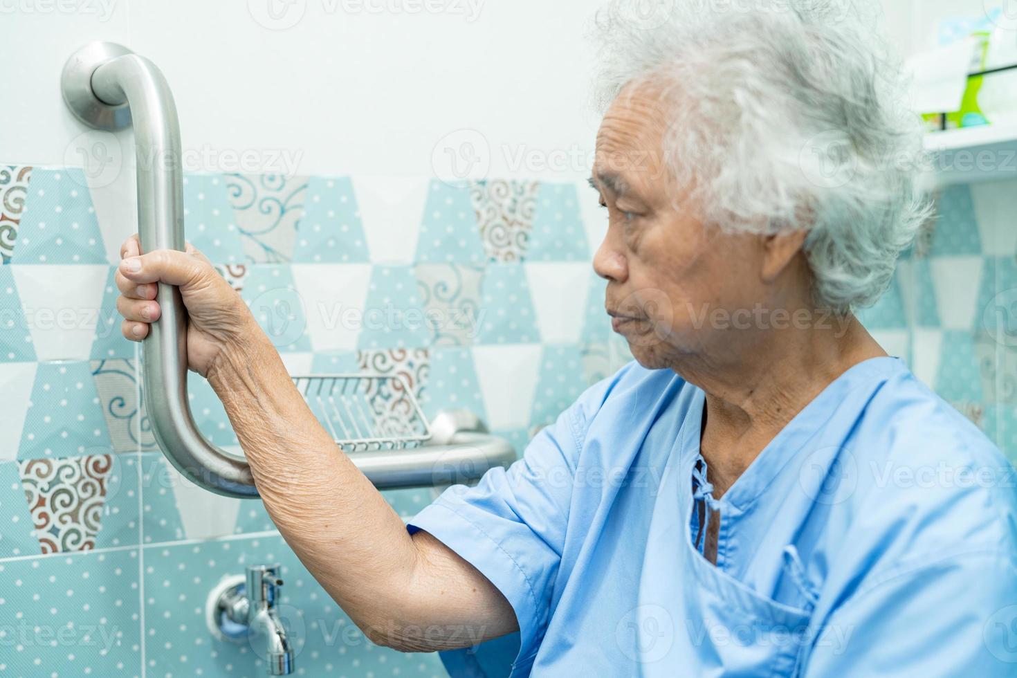 Aziatische senior vrouw patiënt gebruik helling loopbrug handvat beveiliging met help support assistent in verpleegafdeling ziekenhuis. foto