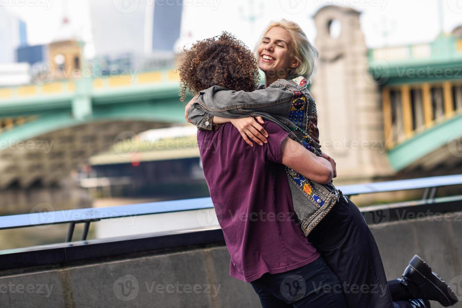 gelukkig paar knuffelen in de buurt van de Southwark-brug over de rivier de Theems, Londen foto