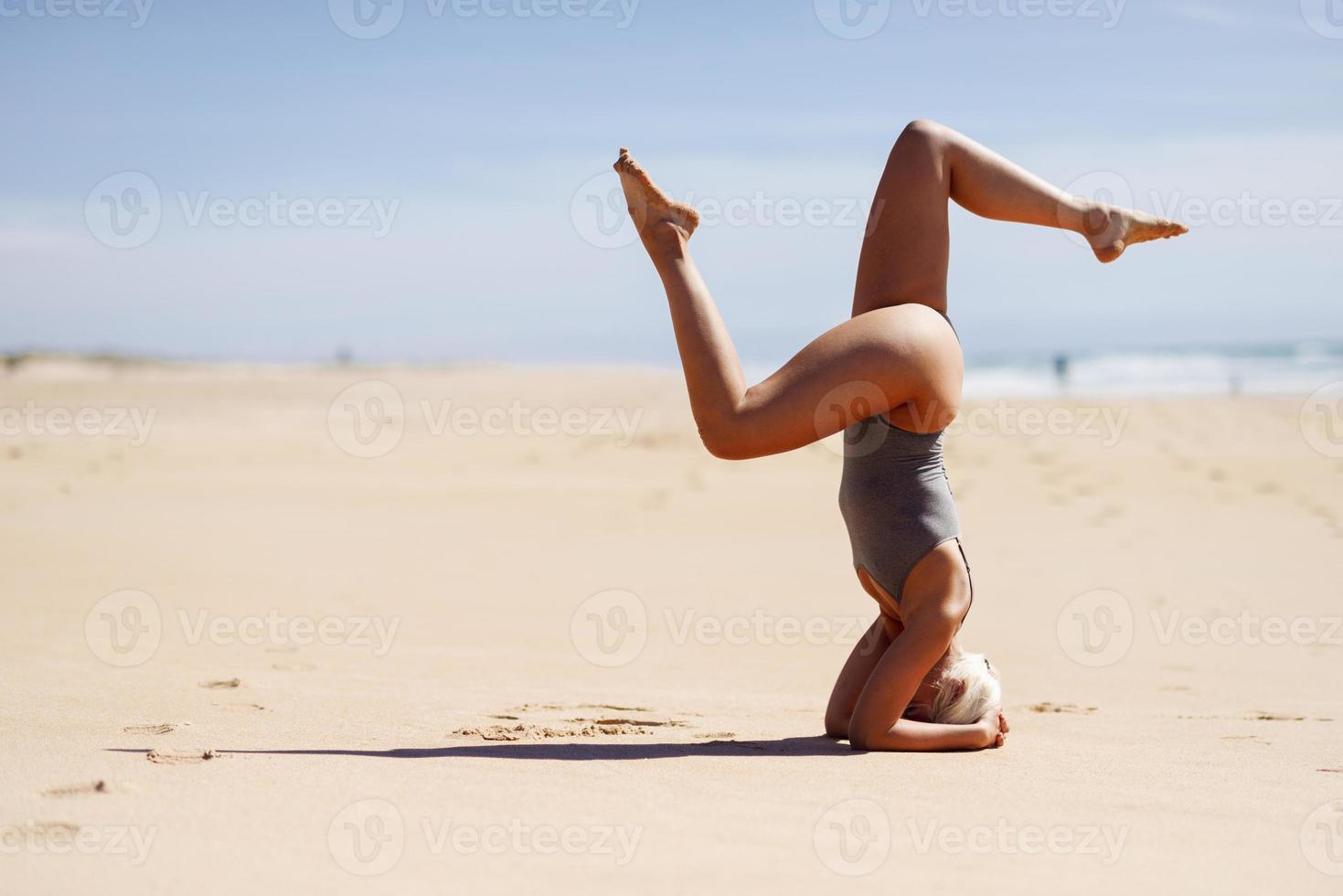 Kaukasische blonde vrouw die yoga beoefent op het strand foto