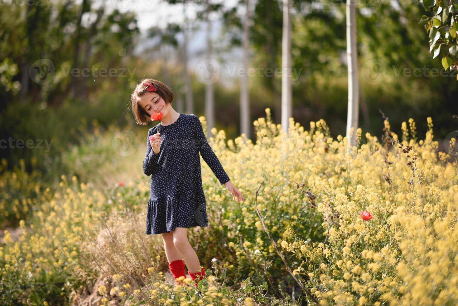 klein meisje dat in het natuurveld loopt en een mooie jurk draagt foto