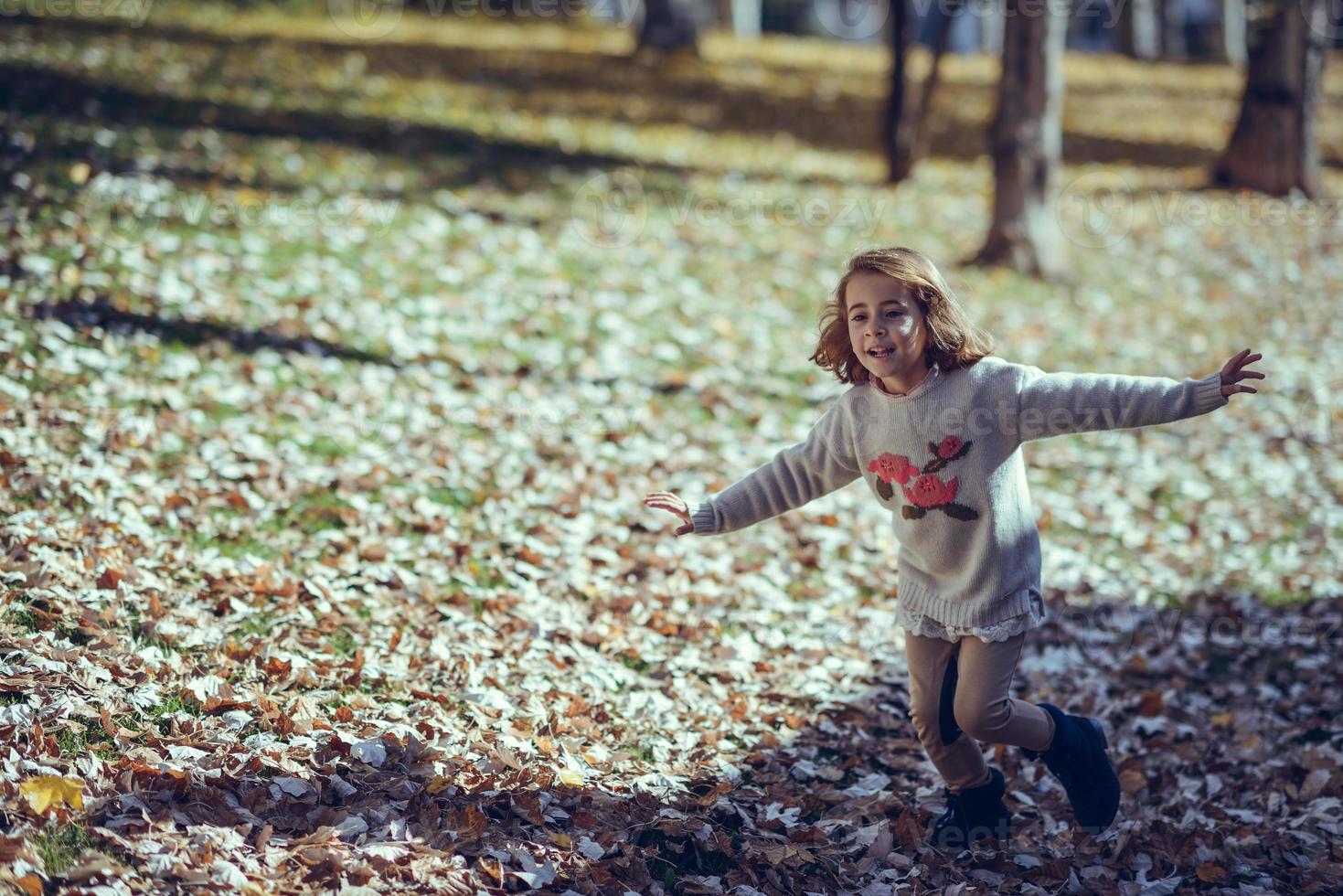 klein meisje speelt in een stadspark in de herfst foto