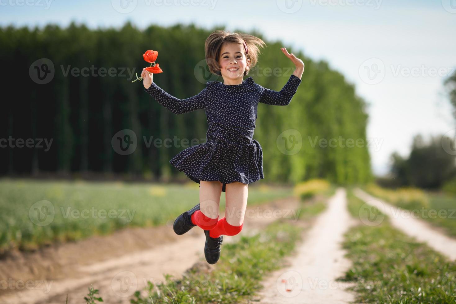 klein meisje dat in het natuurveld loopt en een mooie jurk draagt foto