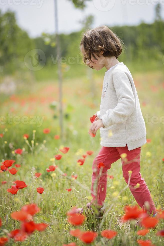 schattig klein meisje dat plezier heeft in een papaverveld foto