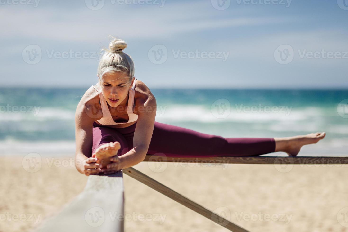 Kaukasische blonde vrouw die yoga beoefent op het strand foto