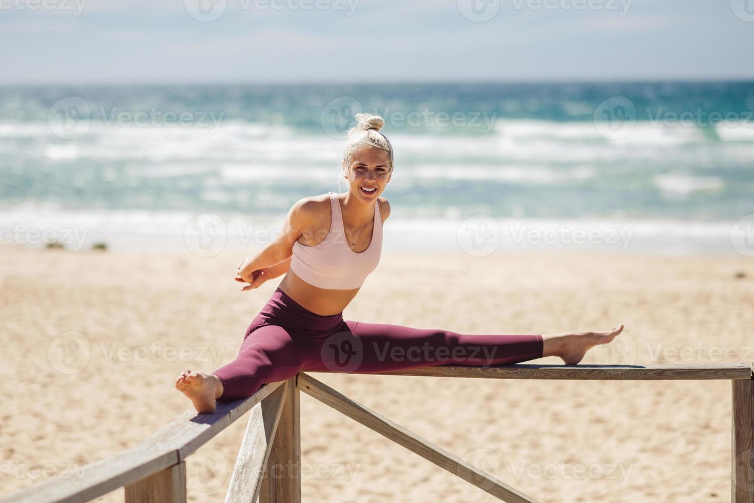 Kaukasische blonde vrouw die yoga beoefent op het strand foto