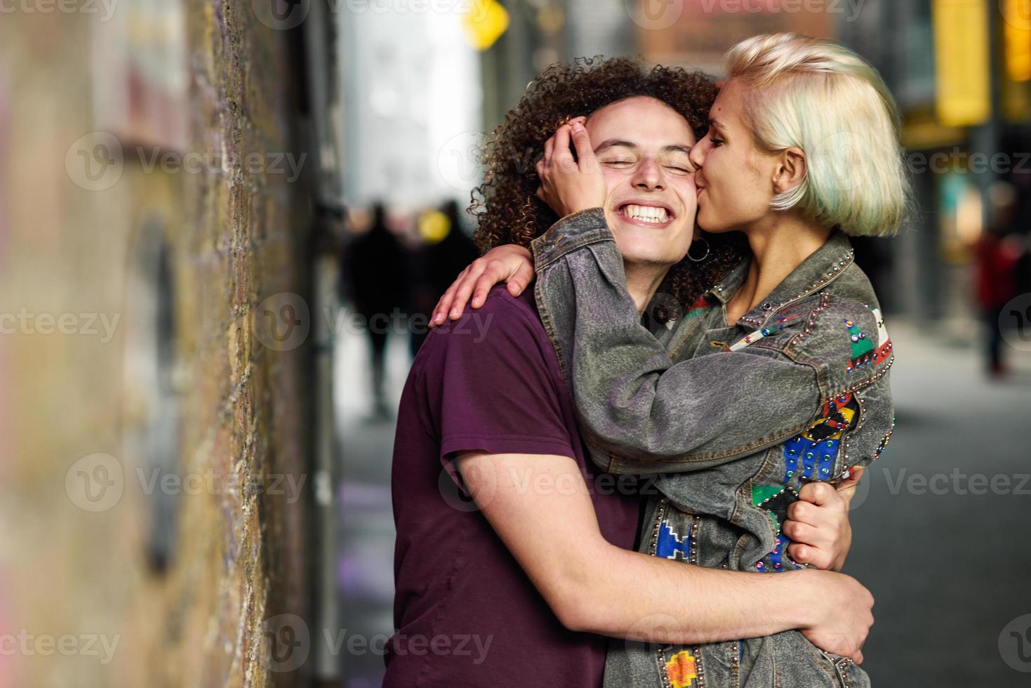 jonge vrouw die haar vriendje kust in een stedelijke achtergrond in een typische Londense straat foto