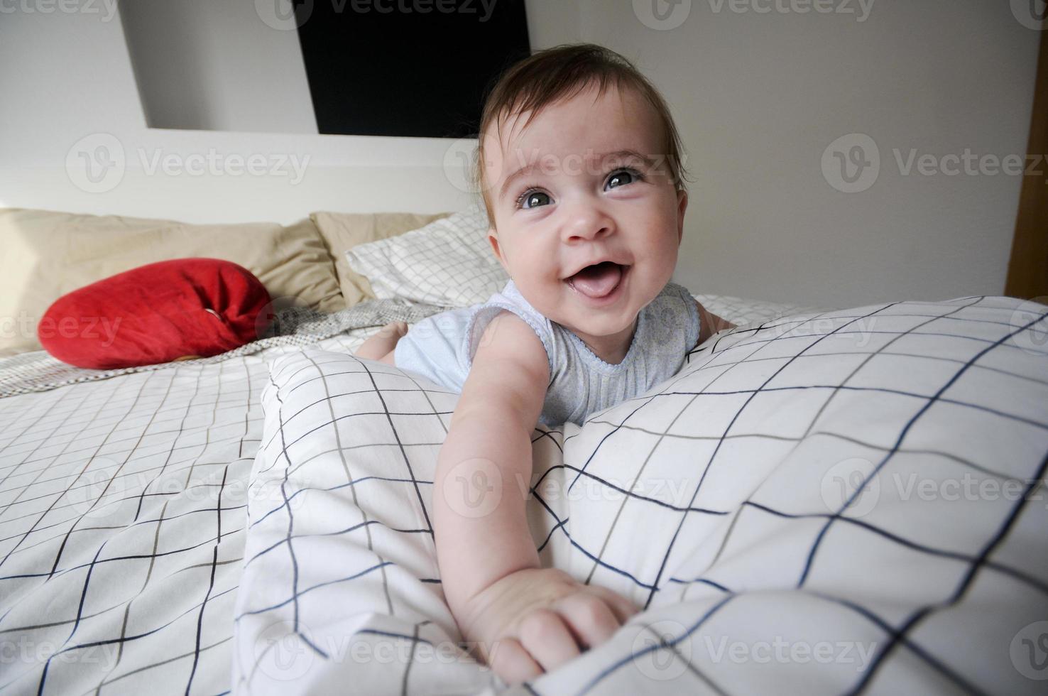 babymeisje liggend op het bed van haar ouders met grappige uitdrukking foto