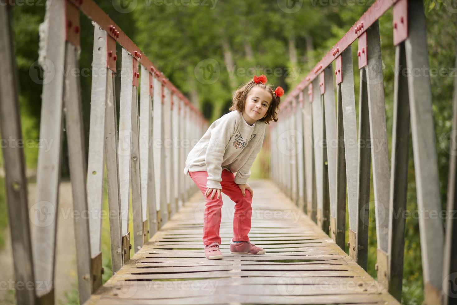 schattig klein meisje dat plezier heeft in een landelijke brug foto