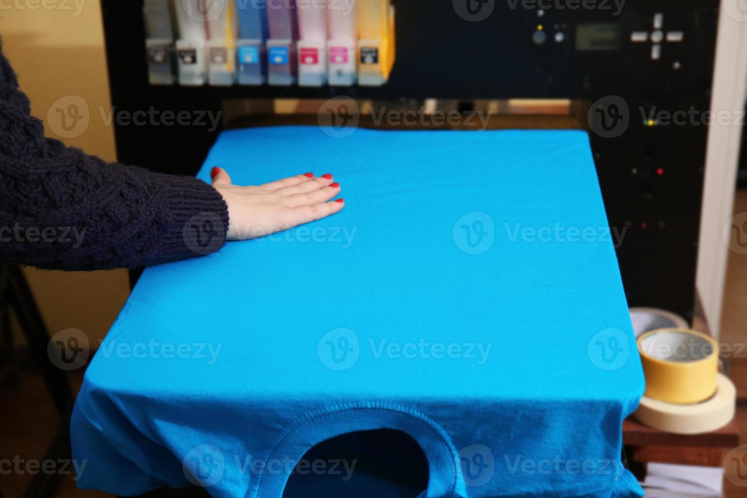 jonge vrouw staande in de buurt van drukmachine met t-shirt op workshop foto