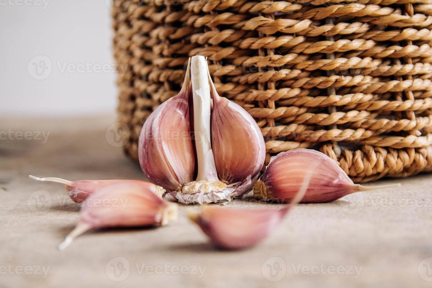 knoflook in een rieten mand op een houten tafel achtergrond foto