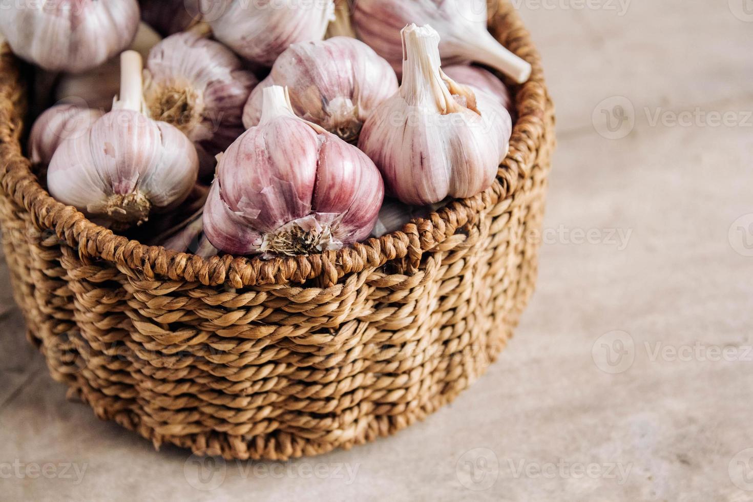 knoflook in een rieten mand op een houten tafel achtergrond foto