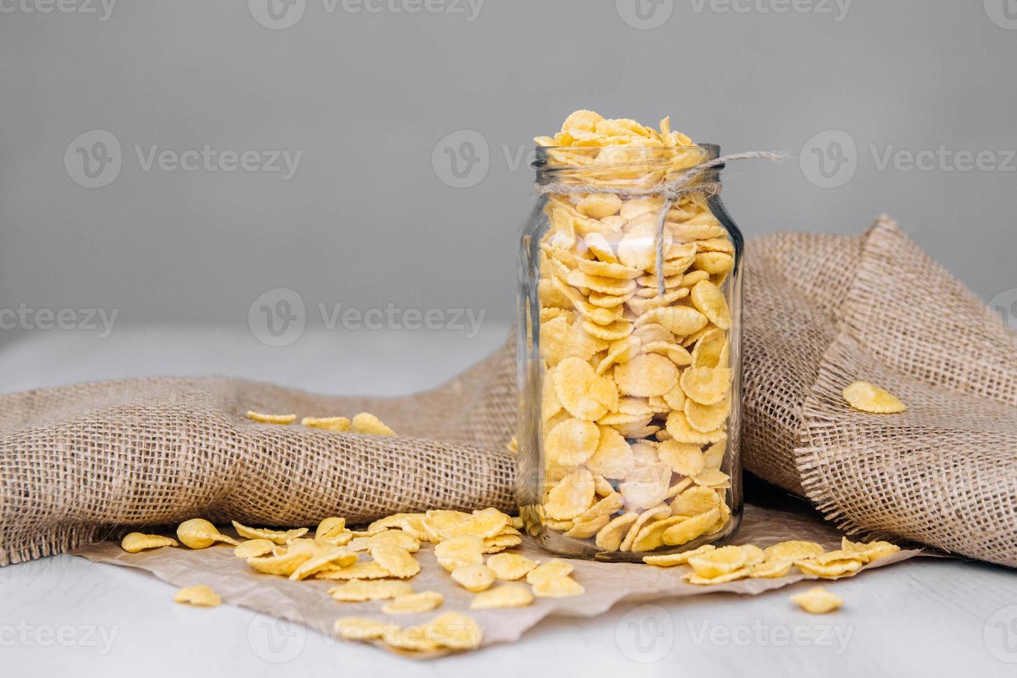 cornflakes in een glazen pot op een witte houten ondergrond foto