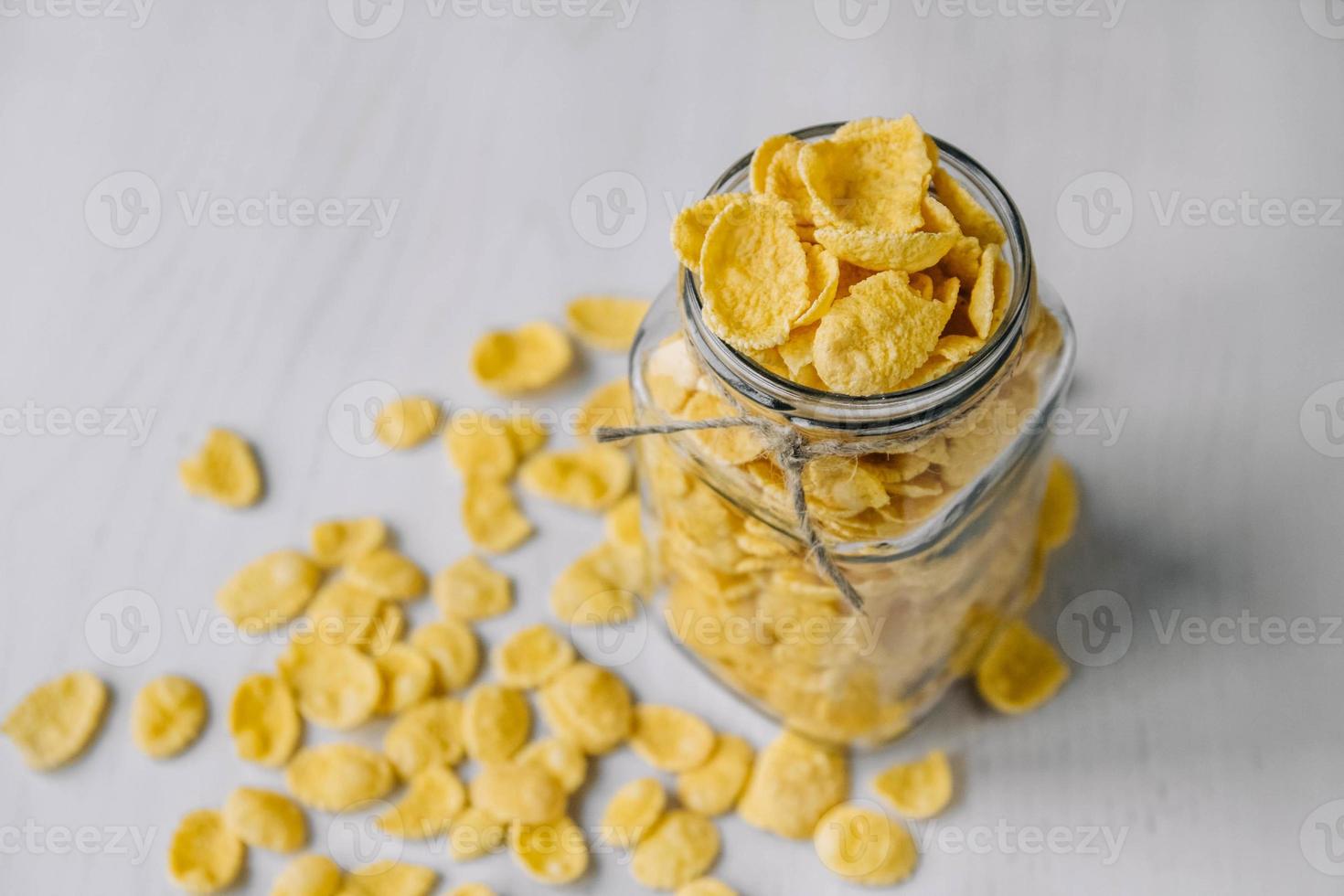 cornflakes in een glazen pot op een witte houten ondergrond foto