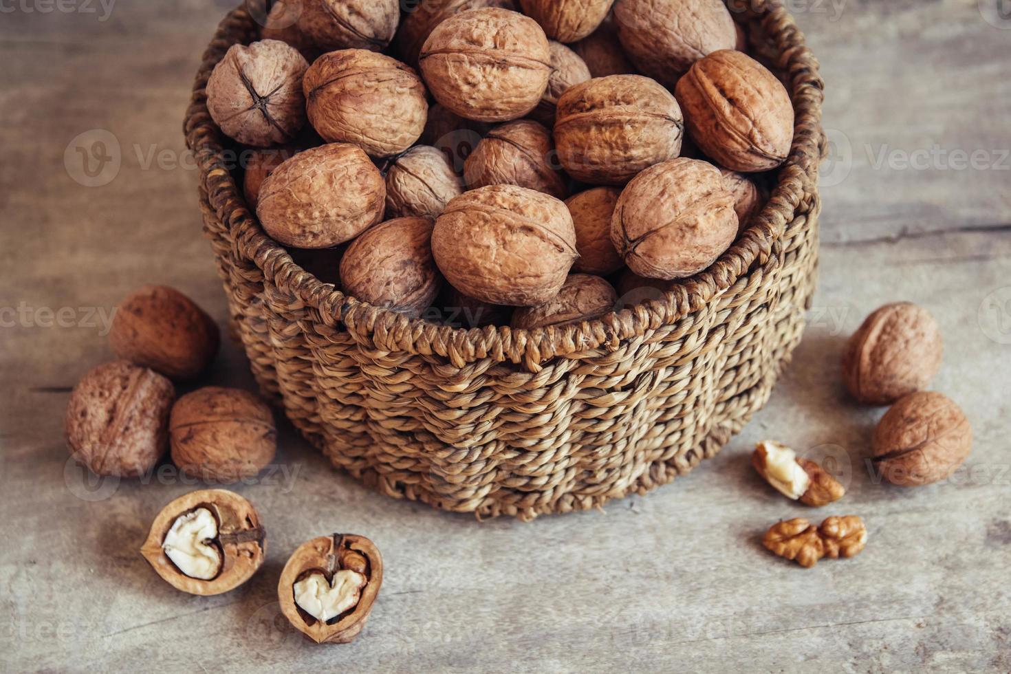 walnoten in een ronde rieten mand op een houten ondergrond foto
