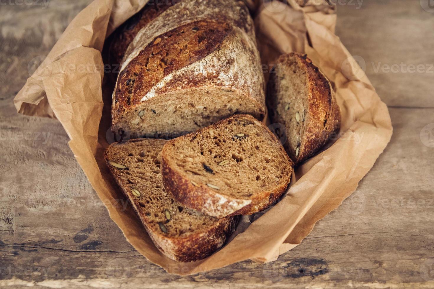 bruin vers brood met zaden wordt in stukjes gesneden op oude houten ondergrond foto