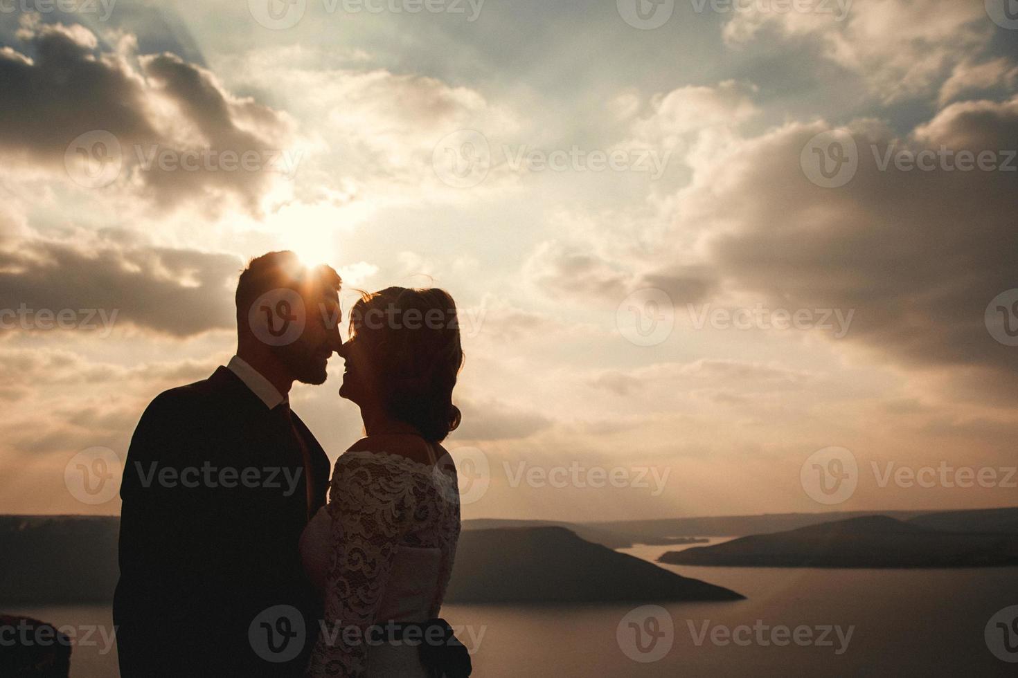 bruidspaar, bruid en bruidegom hand in hand op een achtergrond van bergen en rivieren foto