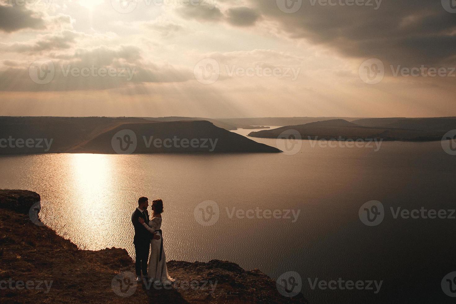 bruidspaar, bruid en bruidegom hand in hand op een achtergrond van bergen en rivieren foto