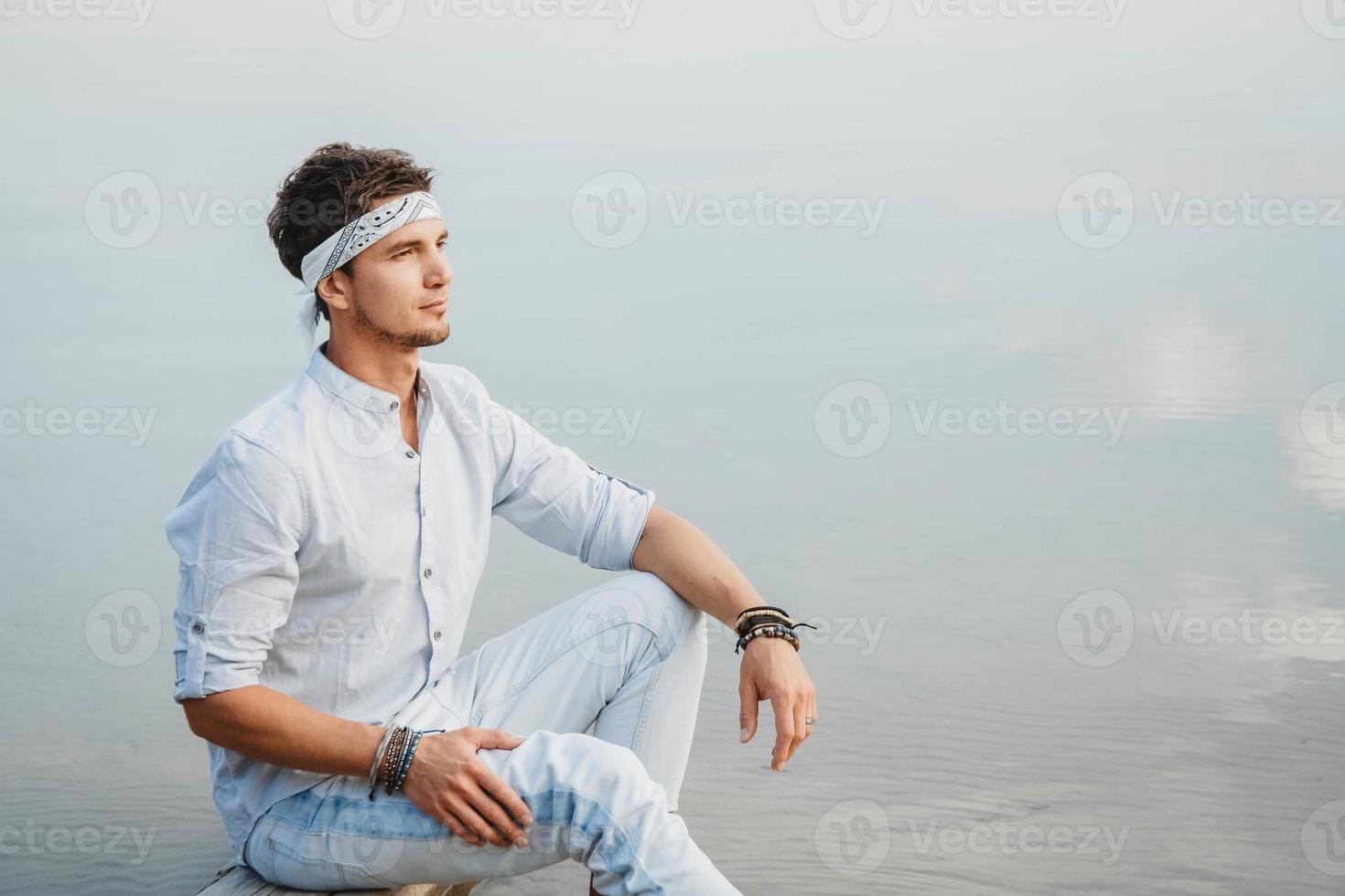 man zit op houten brug en kijkt naar water foto